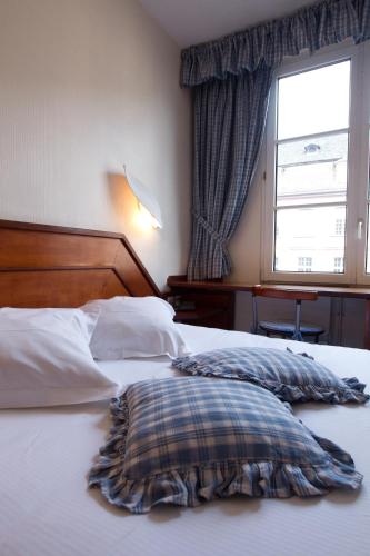 a bed with a pillow on it with a window at Hotel Suisse in Strasbourg