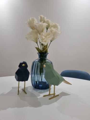a blue vase with white flowers on a table at Blue Beach Apartment - Caminhos de Santiago-Airport in Praia de Angeiras
