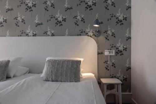 a bedroom with a white bed with a lamp and wallpaper at Best Western Solhem Hotel in Visby
