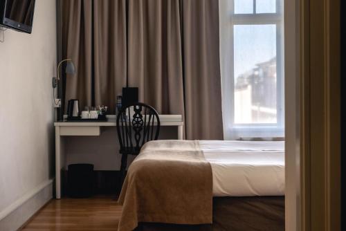 a bedroom with a bed and a desk and a window at Best Western Solhem Hotel in Visby
