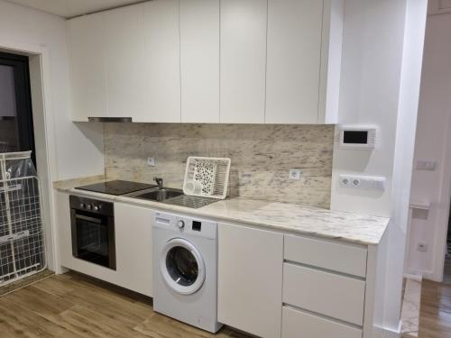 a white kitchen with a sink and a washing machine at Blue Beach Apartment - Caminhos de Santiago-Airport in Praia de Angeiras