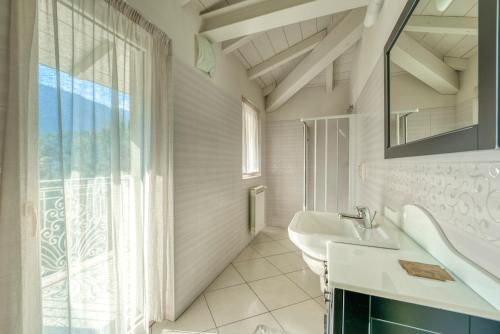 Baño blanco con lavabo y espejo en Villa Liberty, en Darfo Boario Terme