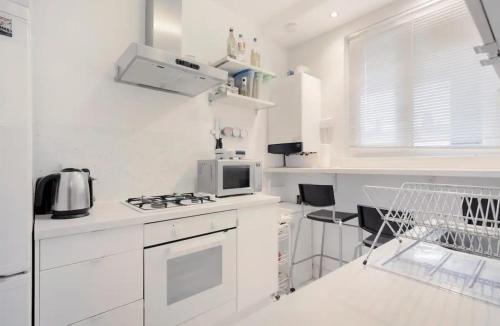 a white kitchen with a stove and a microwave at The Lovely Room in London