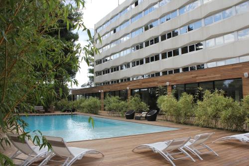 a swimming pool in front of a building at HÔTEL C SUITES chambres spacieuses in Nîmes