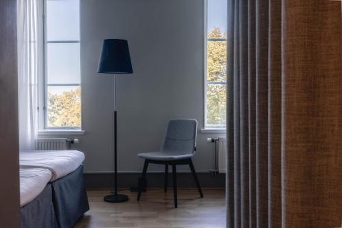 a bedroom with a chair and a lamp and window at Best Western Solhem Hotel in Visby