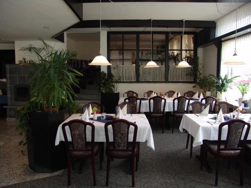 a dining room with tables and chairs and potted plants at Hotel Landhaus Greene in Einbeck