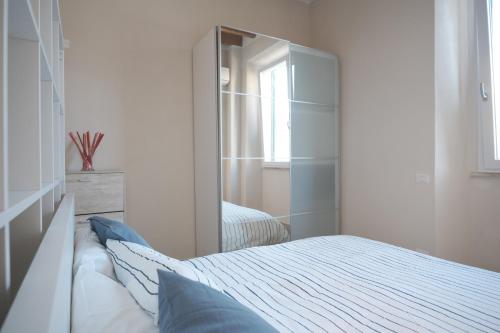 een witte slaapkamer met een bed en een spiegel bij Green Coast House 3 in Piombino