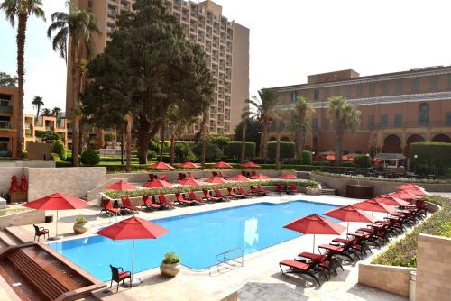 una piscina con sombrillas y sillas rojas en Cairo Marriott Hotel & Omar Khayyam Casino en El Cairo