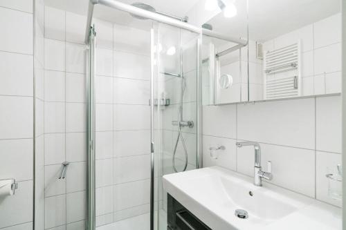 y baño blanco con lavabo y ducha. en Haus-Kaept-n-Hein-Cors, en Wenningstedt