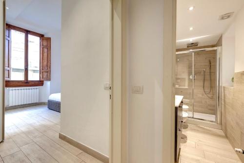 baño con ducha a ras de suelo y puerta de cristal en Baldovini Apartment by Mamo Florence, en Florencia