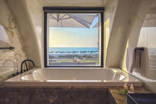 La salle de bains est pourvue d'une grande baignoire et d'une fenêtre. dans l'établissement Africa Jade Thalasso, à Korba