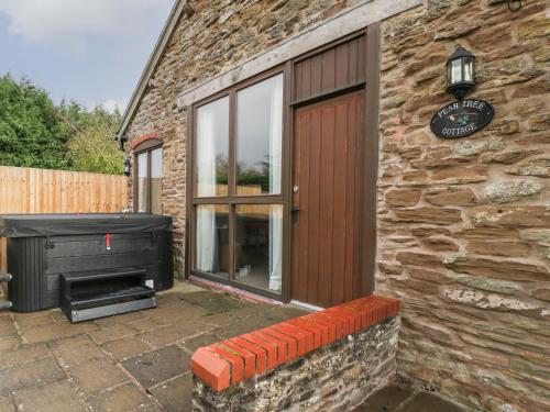 a stone building with a door and a grill at Peartree Cottage in Worcester