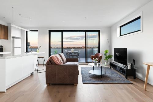 a living room with a couch and a television at Queensview168 Apartments Moonee Ponds in Melbourne