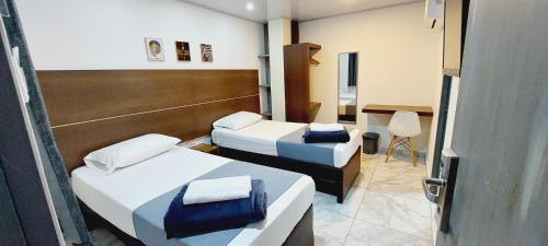 a hotel room with two beds and a desk at HOTEL A & A SANTA ALEJANDRIA in Medellín