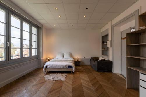 - une chambre avec un lit, un canapé et des fenêtres dans l'établissement Résidence Harmonie Appartement N 1 Haut de gamme Avec Petit Déjeuner, à Néris-les-Bains