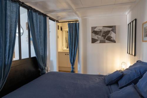 1 dormitorio con cama azul y cortinas azules en La Martinoise Studio, en Saint-Martin-de-Ré