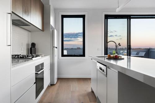 a kitchen with white counters and large windows at Queensview168 Apartments Moonee Ponds in Melbourne