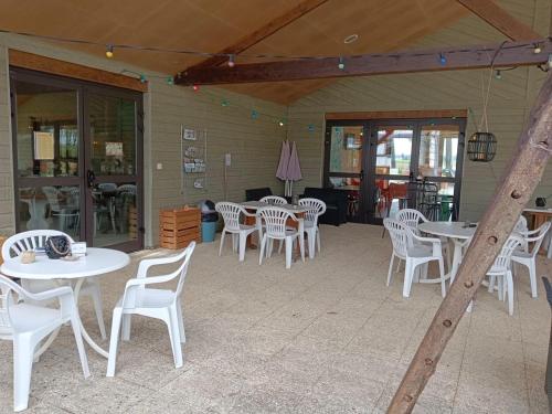 a patio with white tables and white chairs at Camping La Maltournée in Sigloy