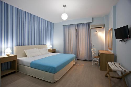 a hotel room with a bed and a tv at Valente Perlia Rooms in Poros