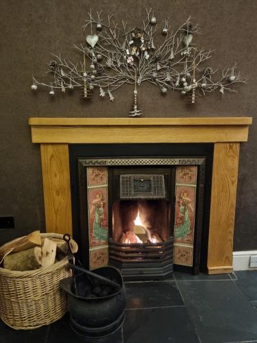 a fireplace with a fire in it and a basket at Tyn Rhos Country House in Caernarfon