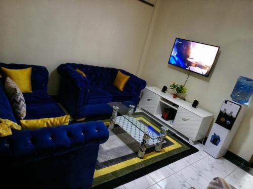 a living room with a blue couch and a tv at SAFNEST Furnished Apartment in Nakuru