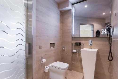 a bathroom with a toilet and a glass shower at Hugo's Boutique Hotel - Adults Only in St Julian's