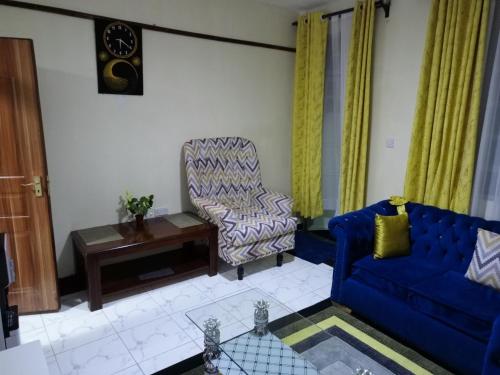 a living room with a blue couch and a chair at SAFNEST Furnished Apartment in Nakuru