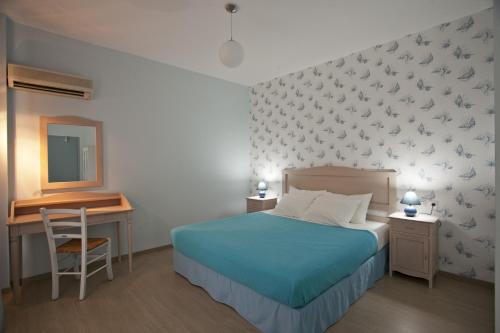 a bedroom with a bed and a desk with a mirror at Valente Perlia Rooms in Poros