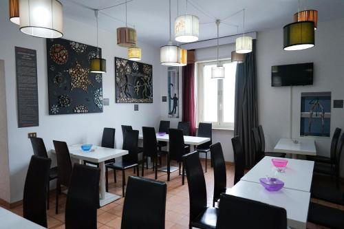 Roma Room Hotel في روما: غرفة طعام مع طاولات بيضاء وكراسي سوداء