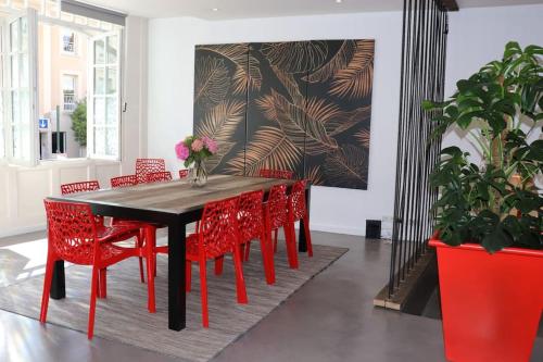 une salle à manger avec une table et des chaises rouges dans l'établissement Dinard : loft de 175 m² - à 150 m de la plage, à Dinard