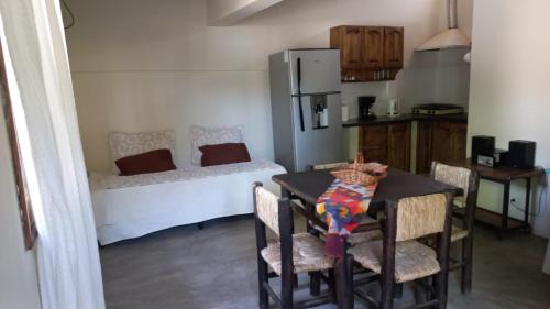 een keuken met een tafel en een slaapkamer met een bed bij el remanso in San Agustín de Valle Fértil