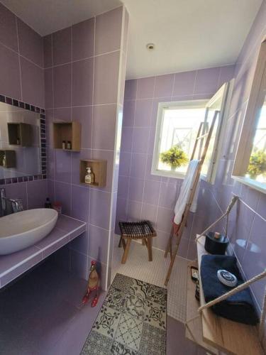 d'une salle de bains pourpre avec baignoire et lavabo. dans l'établissement Villa au cœur de la forêt, à Avensan