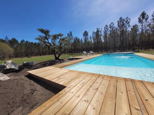 - une piscine avec une terrasse en bois à côté d'une cour dans l'établissement Villa au cœur de la forêt, à Avensan