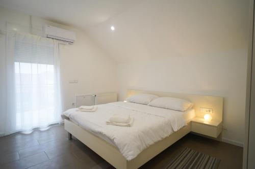 a white bedroom with a bed with two towels on it at Apartments Choice in Velika Gorica