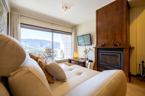 a living room with a white couch and a fireplace at Casa da Tia Douro in Peso da Régua