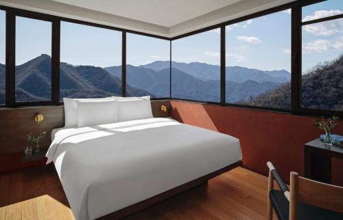 a bedroom with a large white bed in front of windows at Commune by the Great Wall, in the Unbound Collection by Hyatt in Yanqing