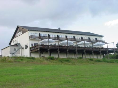 ein großes weißes Gebäude mit einem Balkon auf einem Feld in der Unterkunft Hotel und Gasthaus Rammelburg-Blick in Friesdorf