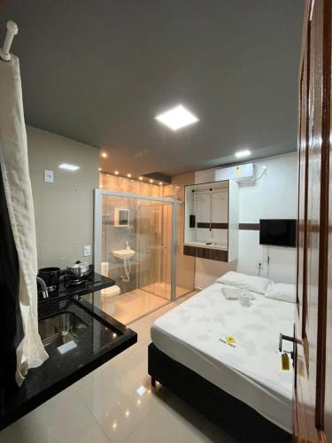 1 Schlafzimmer mit einem weißen Bett und einer Küche in der Unterkunft Pousada Torre Forte in Bujari