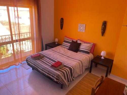 a bedroom with a bed with orange walls and a window at Casa Luana - Rooms in Sagres