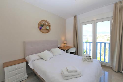 a bedroom with a large white bed with a balcony at Estepona Port Luxury Apartment AURA in Estepona