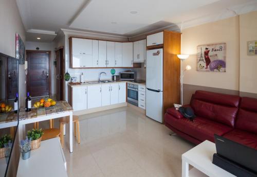 a kitchen and a living room with a red couch at Comfortable apartment with amazing sea views in Palm-Mar