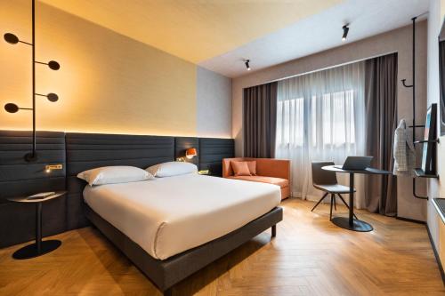 カゼルタにあるNovotel Caserta Sudのベッドとデスクが備わるホテルルームです。