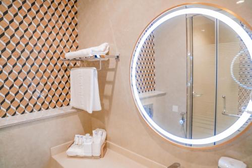 a bathroom with a shower and a large mirror at M14 Hotel Apartment in Ras al Khaimah