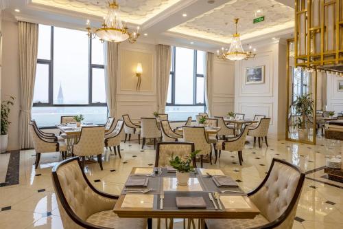 a restaurant with tables and chairs and windows at Meliá Vinpearl Phu Ly in Phủ Lý