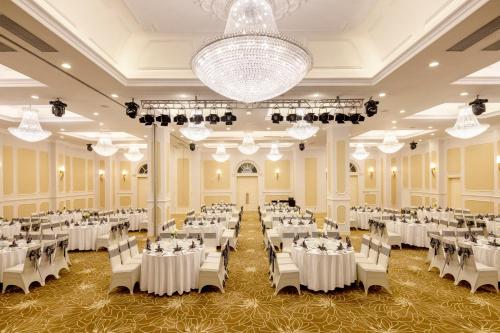 a banquet hall with white tables and chairs and a chandelier at Meliá Vinpearl Phu Ly in Phủ Lý