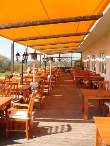 an empty patio with wooden tables and chairs at Hotel und Gasthaus Rammelburg-Blick in Friesdorf