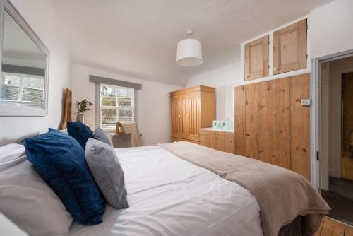 a bedroom with a large white bed with blue pillows at Saffron Cottage, St Ives in St Ives