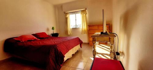 1 dormitorio con cama roja y ventana en Rufilandia Dúplex para 2 personas Zona El Calvario en Tandil