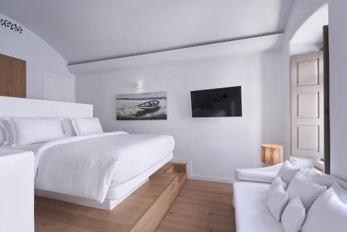 ミコノス・シティにあるWhite Sand Suites Mykonosの白いベッドルーム(ベッド1台、ソファ付)