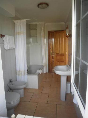 a bathroom with a toilet and a tub and a sink at Pensión Galimar in San Vicente de la Barquera